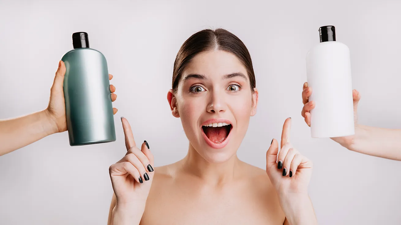 Frau zeigt auf 2 Shampooflaschen